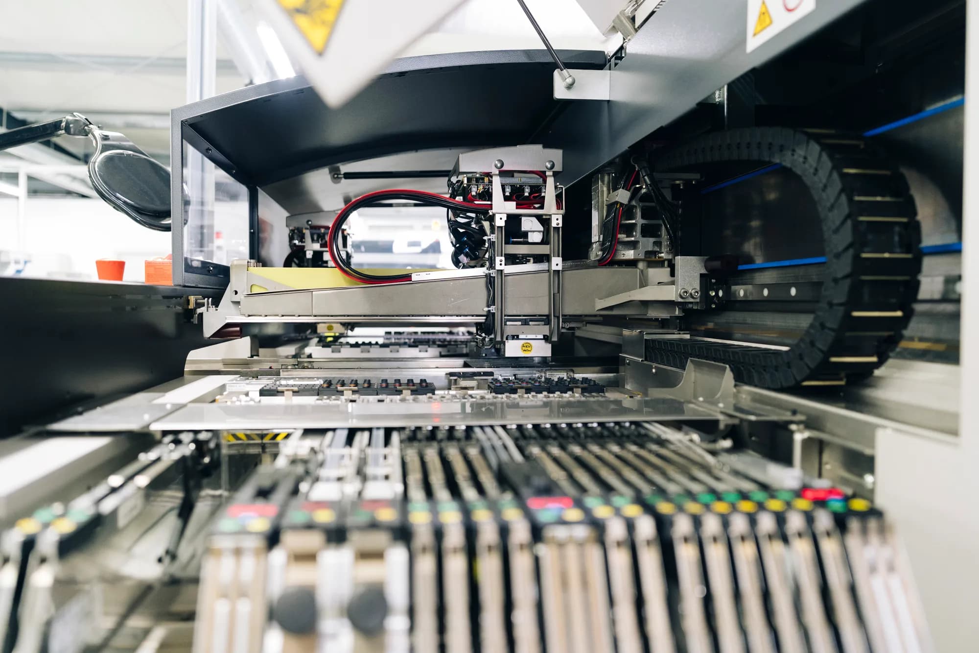 Komplexe Maschine der Baugruppenfertigung: Nahaufnahme von Metallstrukturen, Kabelbäumen und elektronischen Komponenten.