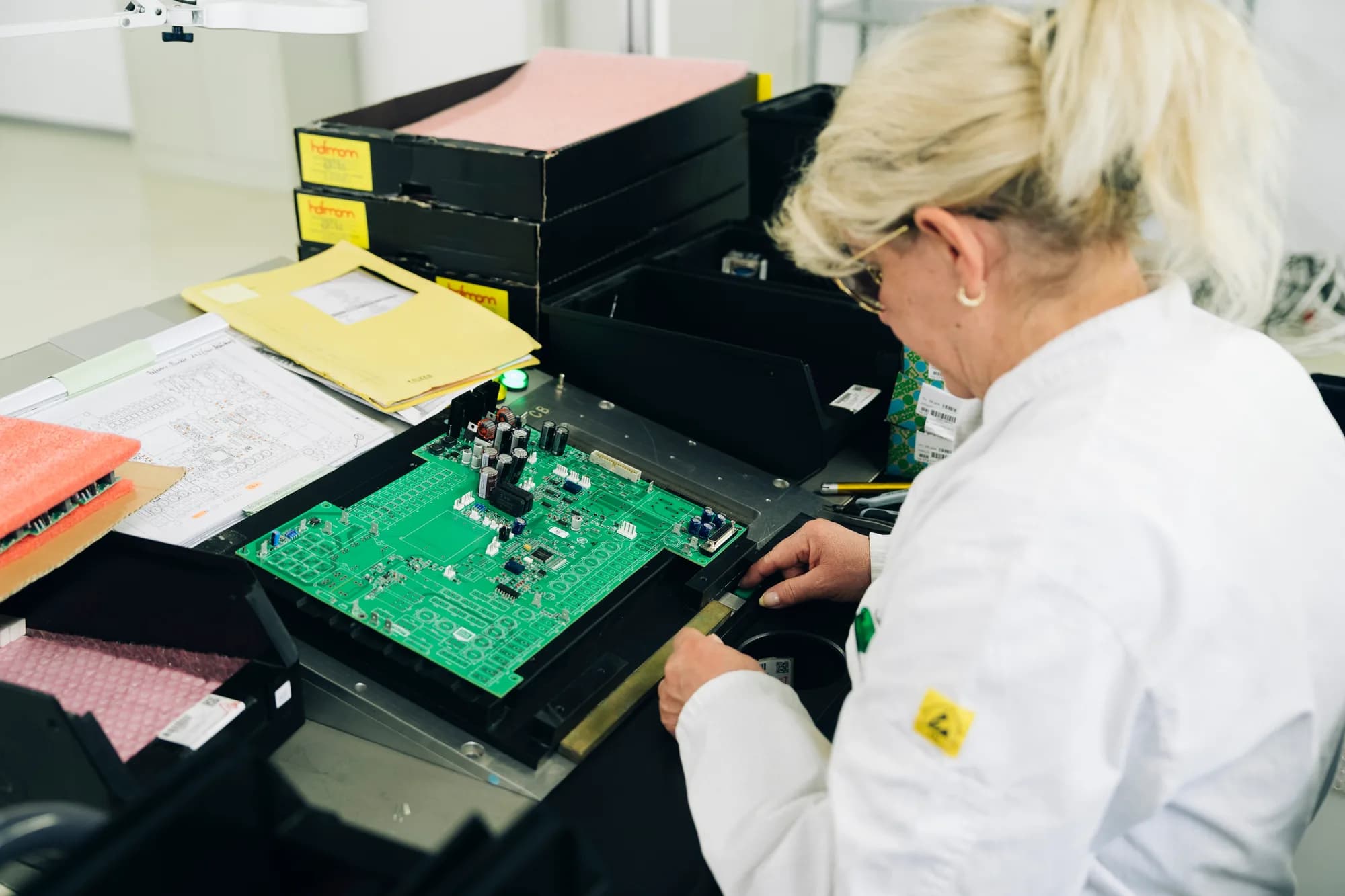 Elektronikfertigung Nürnberg: Ein Mitarbeiter arbeitet konzentriert an einer grünen Platine mit SMD-Bestückung und elektronischen Baugruppen.