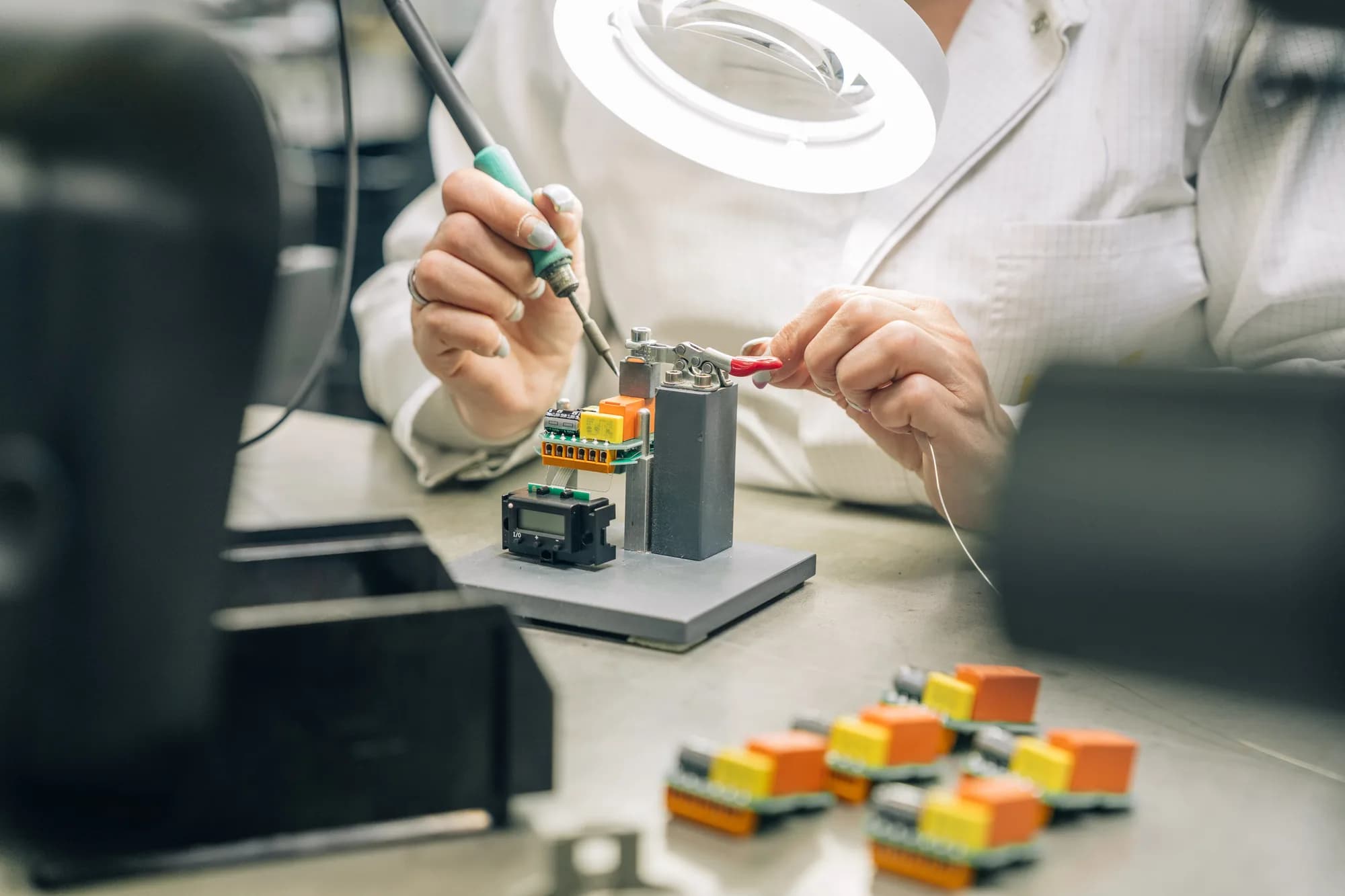 Hand arbeitet an grüner Leiterplatte (PCB). Nahaufnahme der Elektronik-Baugruppenfertigung mit SMD-Bestückung und Chips.